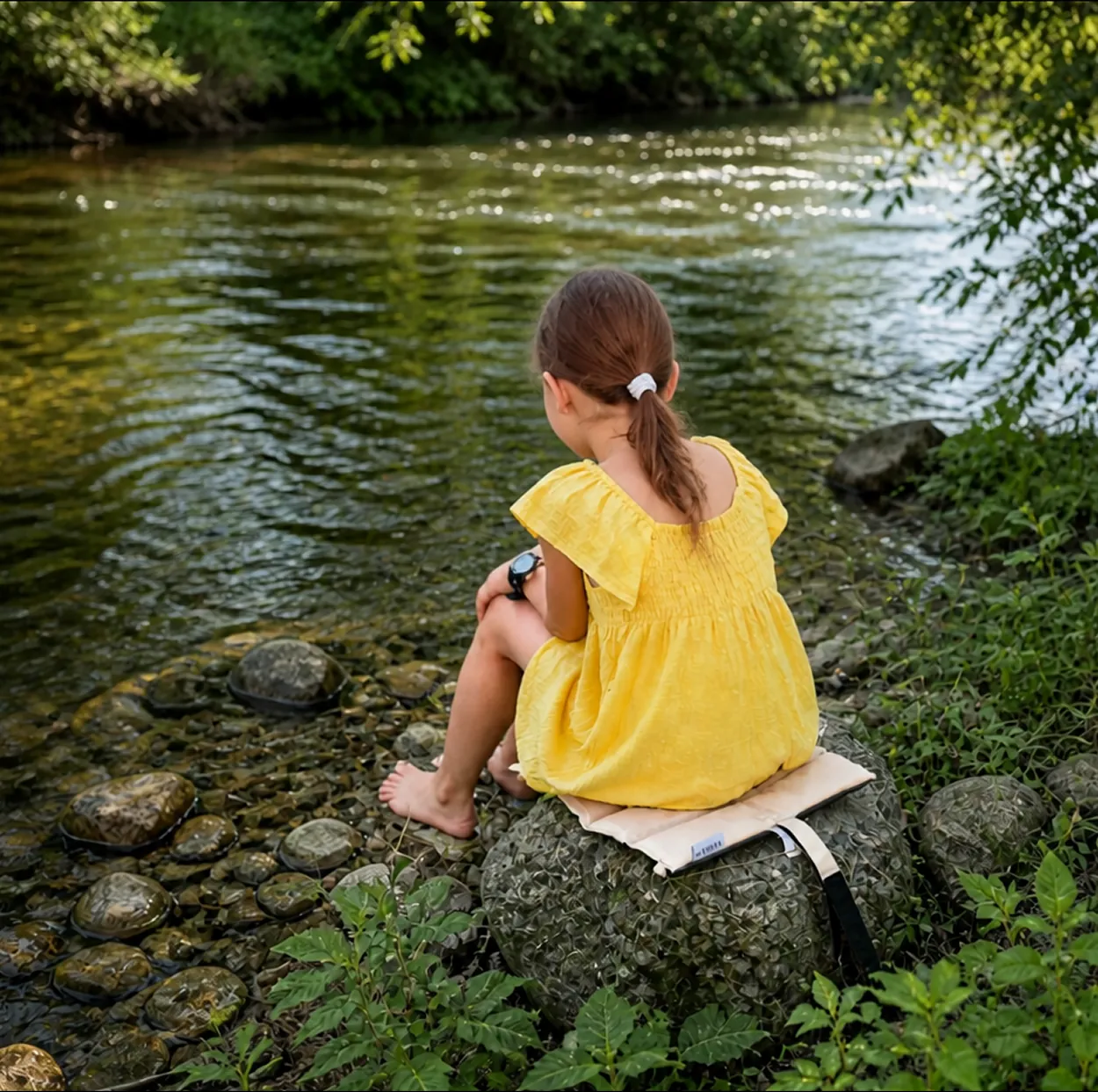Mädchen sitzt am Bach auf dem NELARO Sitzkissen